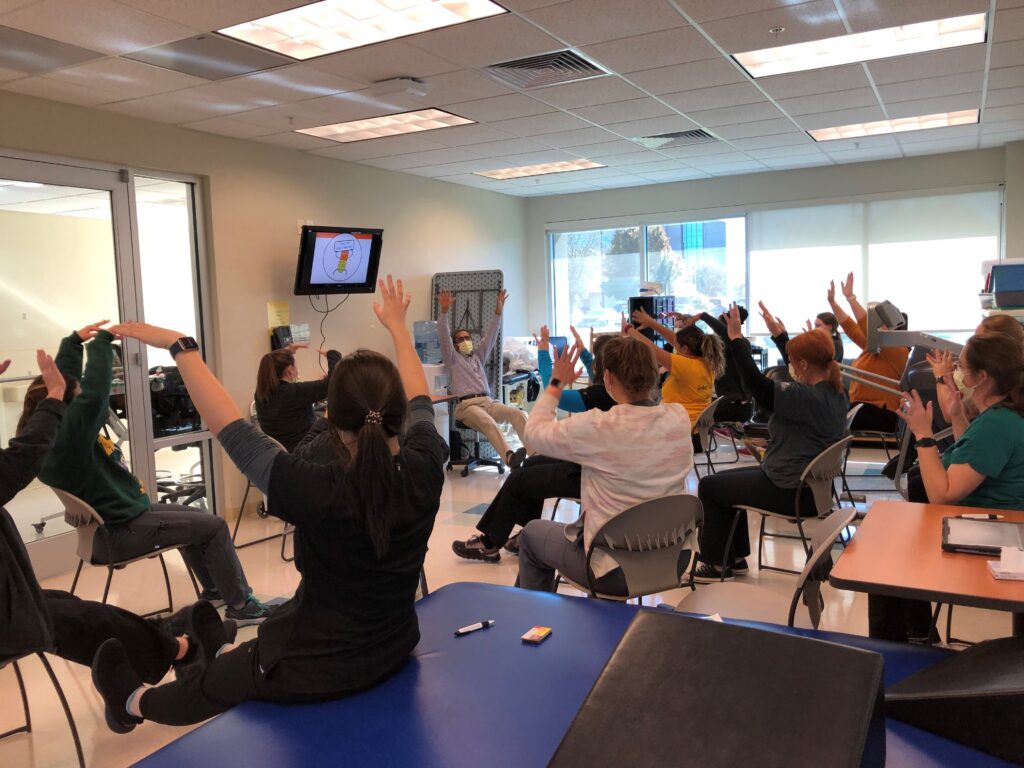 A group class with participants raising hands indoors.