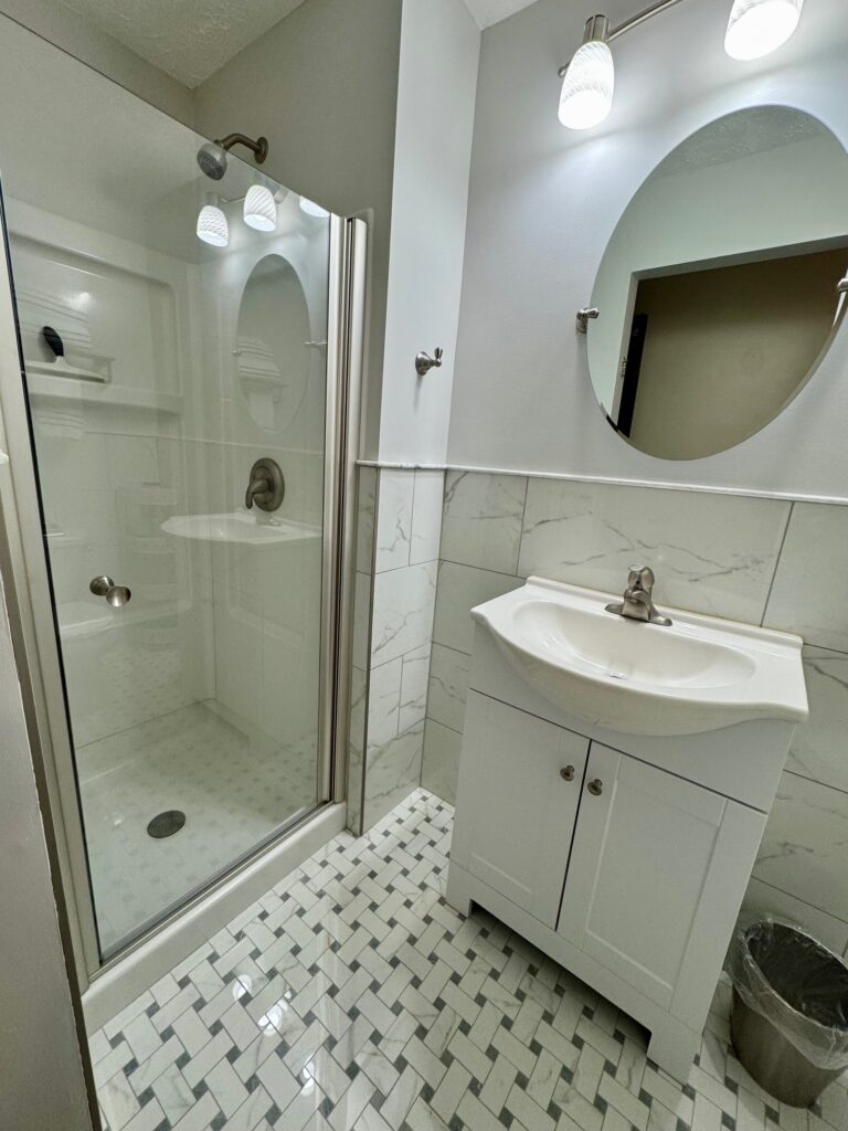 Modern bathroom with glass shower and white vanity.
