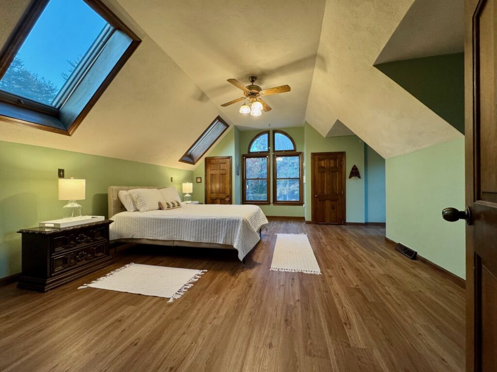 Cozy bedroom with a neatly made bed and green accent wall.